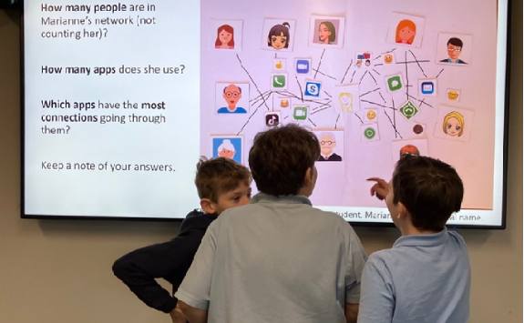 Three school children interacting with a digital whiteboard